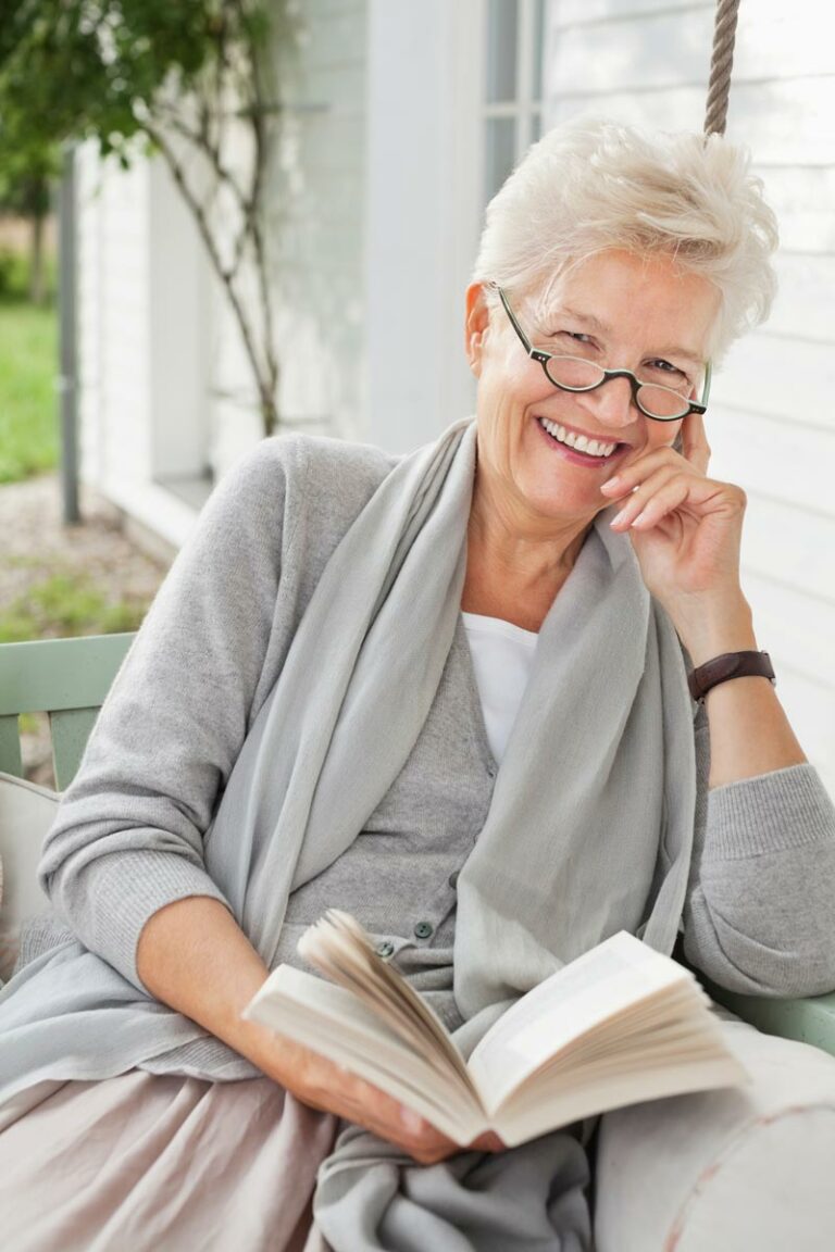 Sun City West Assisted Living | Senior woman reading book on porch in respite care